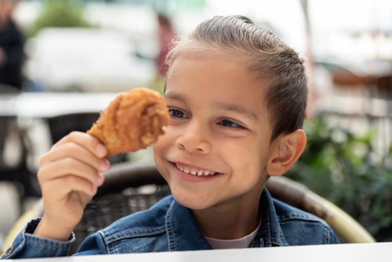 Child holding a piece of fried chicken